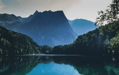 A body of water surrounded by trees and mountains in the background