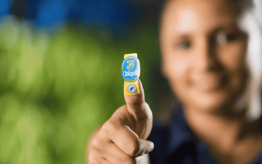 Various people holding up their thumb or finger showing the sticker